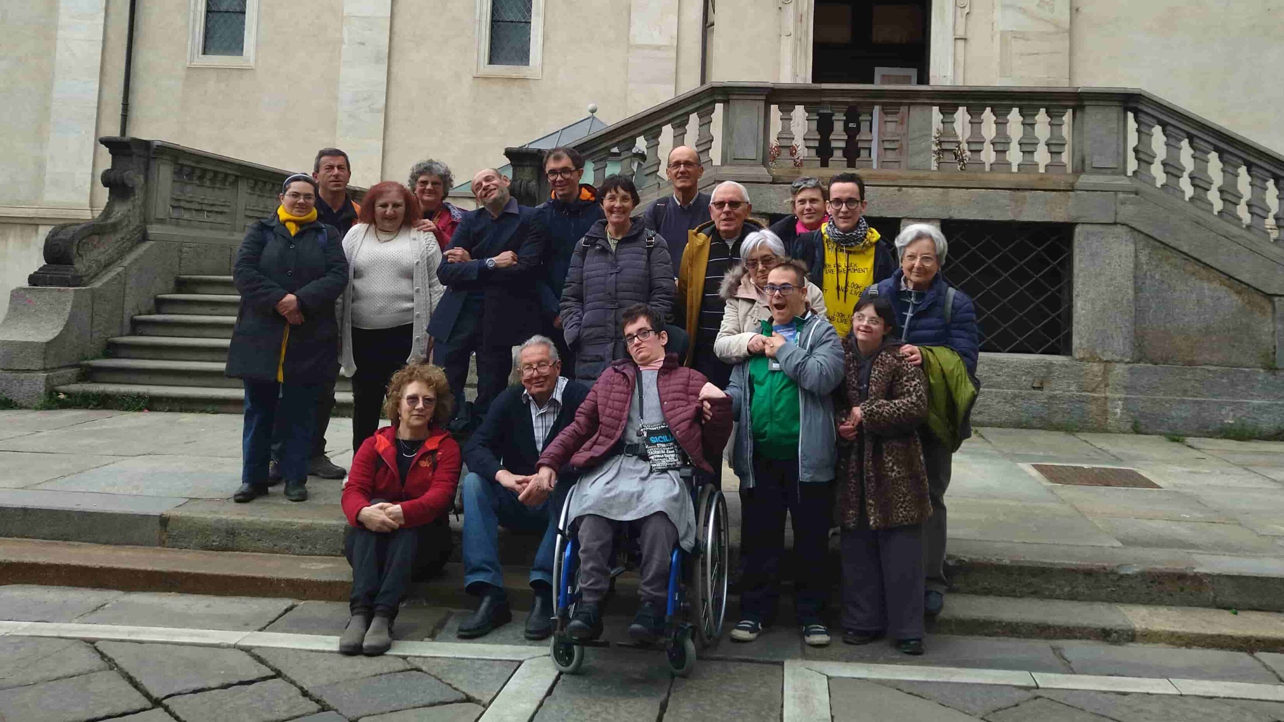 Foto di gruppo di una comunità con una persona sulla sedia a rotelle davanti al Palazzo Reale di Torino