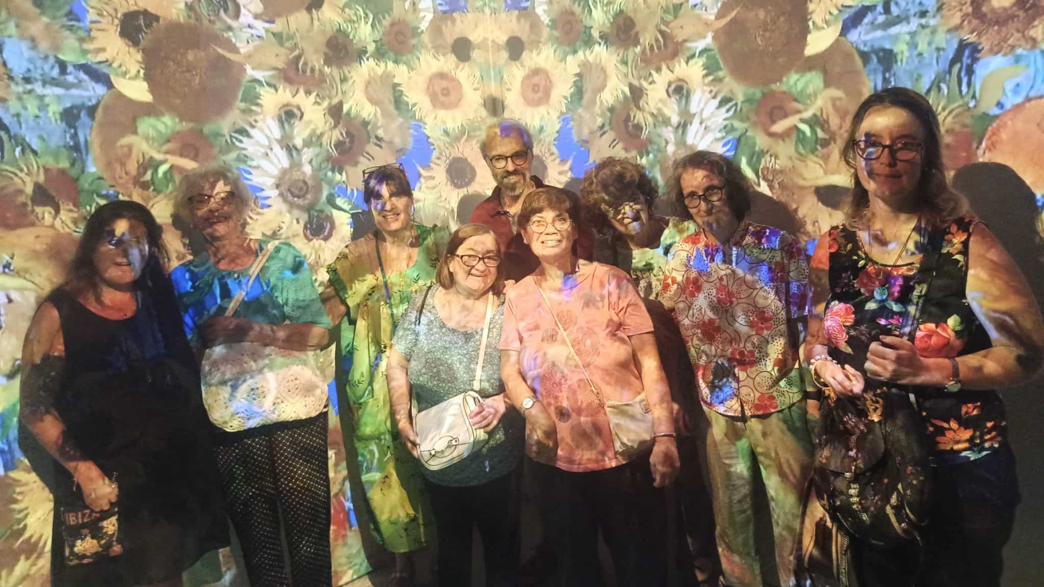 Gruppo di persone su uno sfondo di un quadro di Van Gogh con una luce colorata sopra di loro