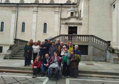 Foto di gruppo di una comunità con una persona sulla sedia a rotelle davanti al Palazzo Reale di Torino